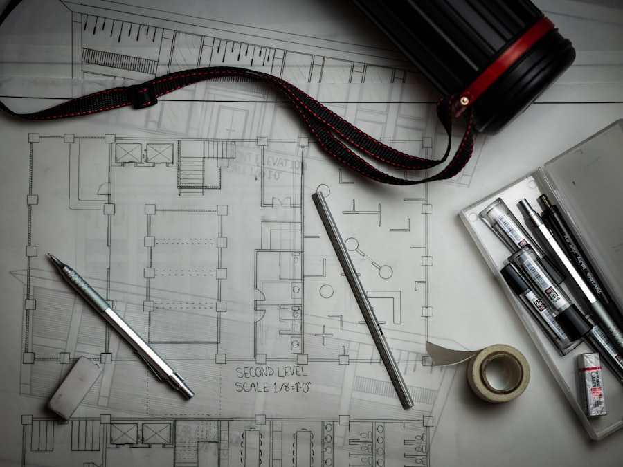 Architectural blueprints with drafting pencils, a metal ruler, and a storage tube