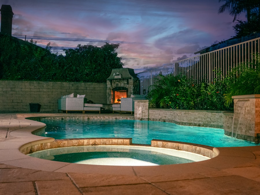 A backyard pool with a built-in circular spa, lit at dusk