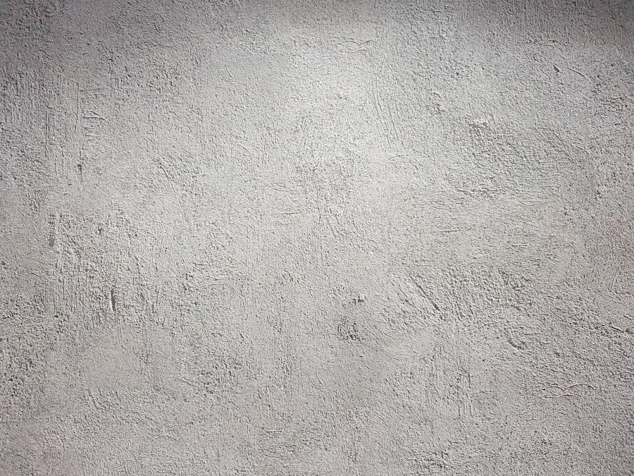 A light grey wall with a rough and uneven plaster texture