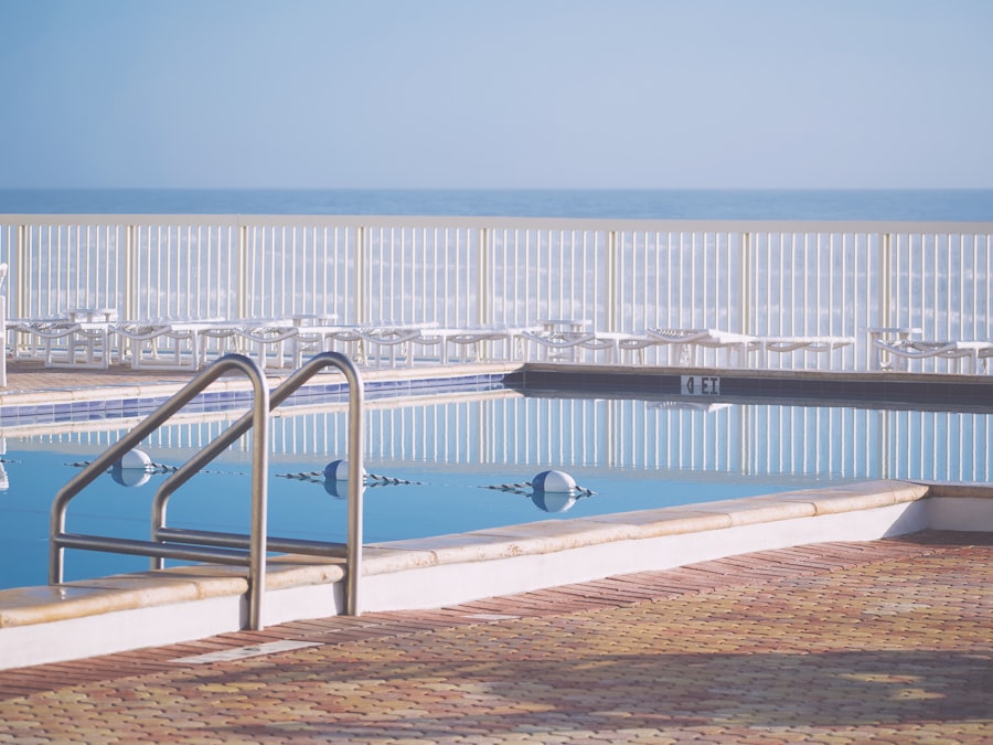 Swimming pool with ocean and chairs in background