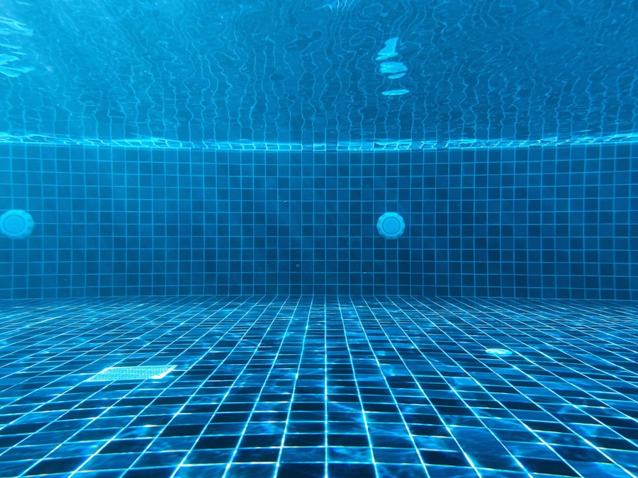 An underwater view of a blue tiled swimming pool with a drain