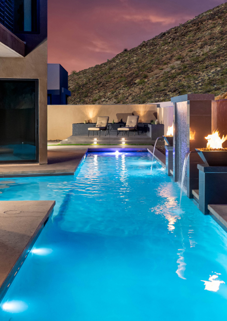 Lap pool with fire features and water spouts at dusk