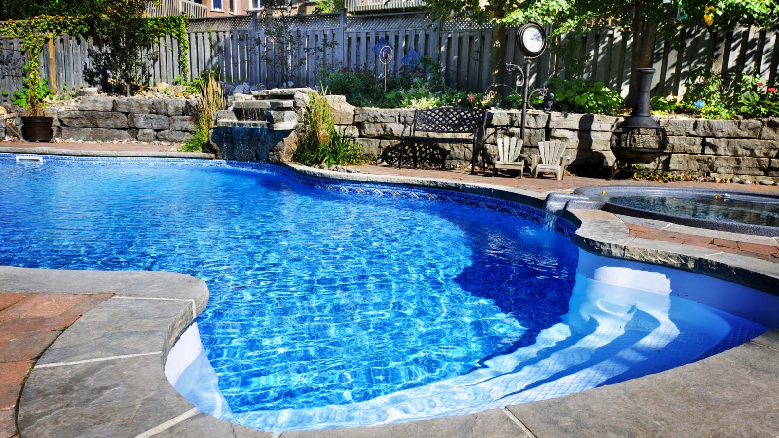 Freeform pool with a stone waterfall and adjoining spa