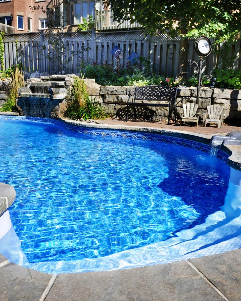 Freeform pool with a stone waterfall and adjoining spa
