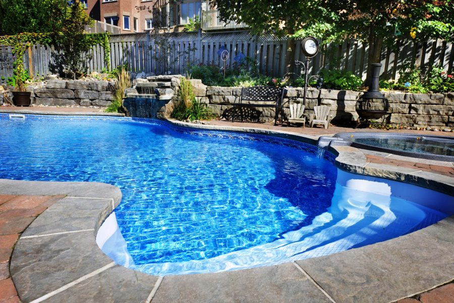 Freeform pool with a stone waterfall and adjoining spa
