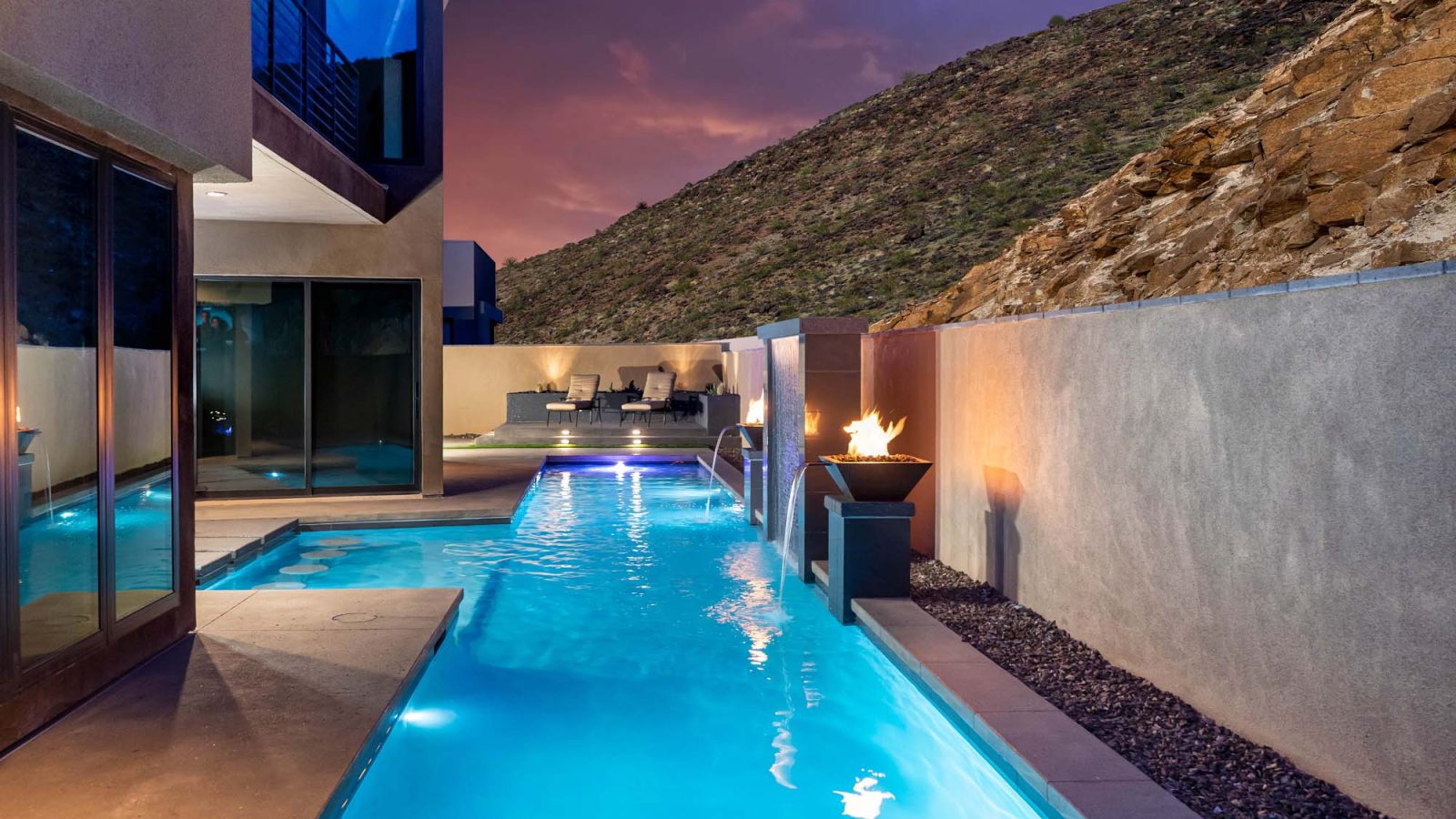 Lap pool with fire bowls lit at dusk