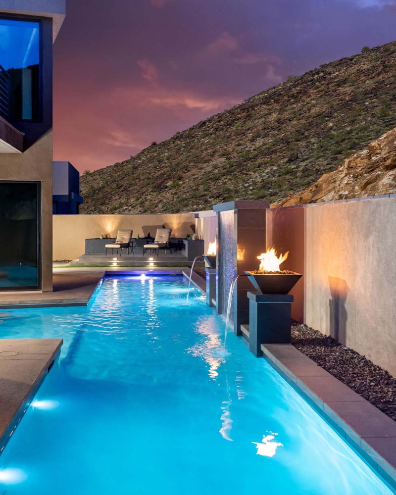 Lap pool with fire bowls lit at dusk