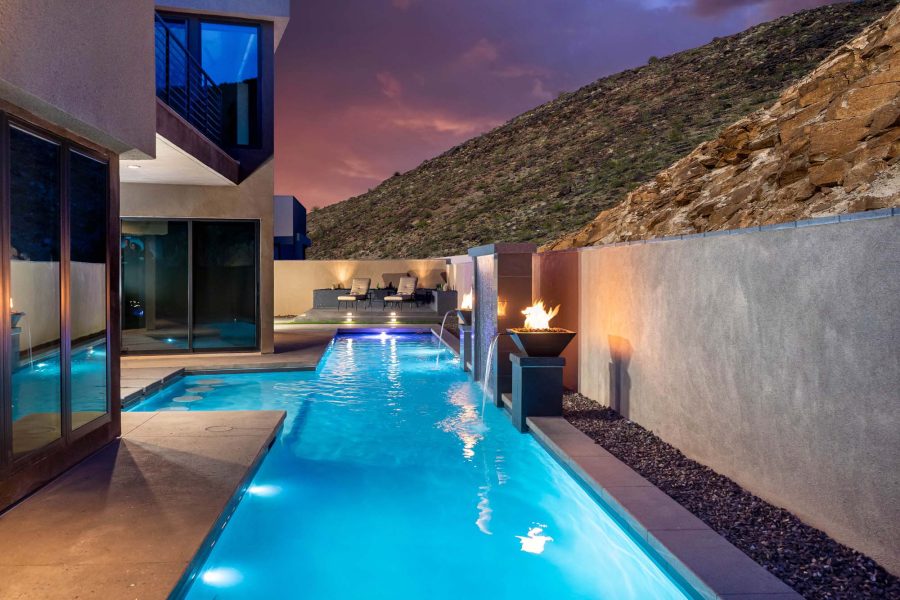 Lap pool with fire bowls lit at dusk