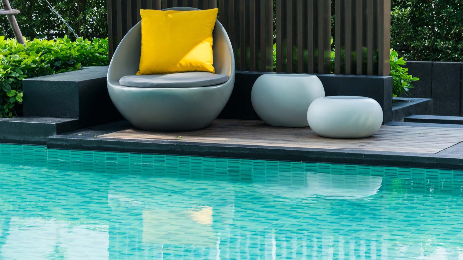 Modern pool with turquoise tile and poolside seating