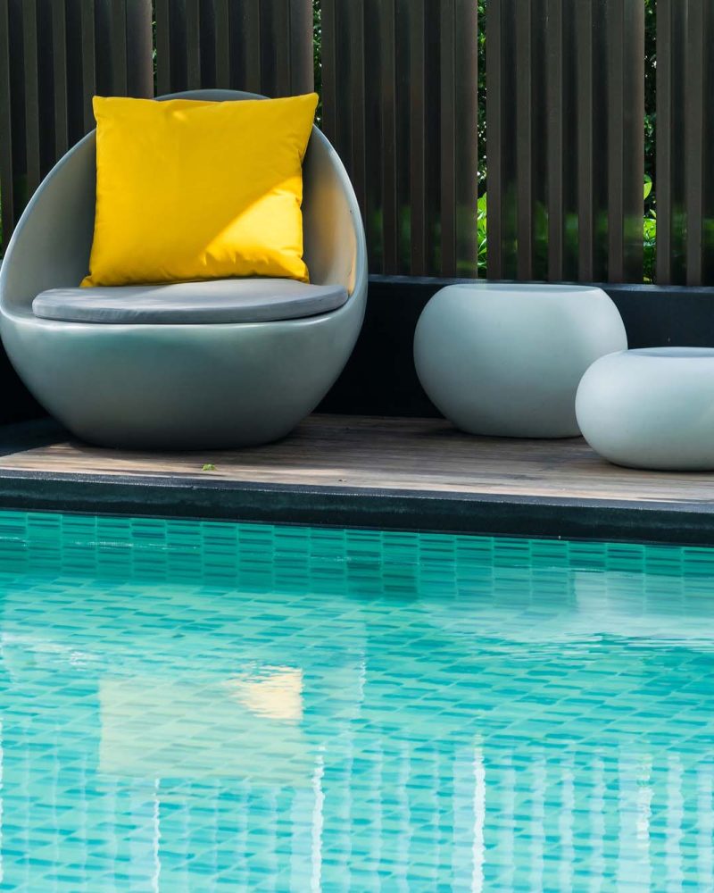 Modern pool with turquoise tile and poolside seating